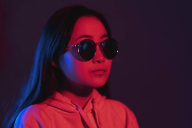 Geceleri neon pembe ve mavi ışıklarla Asyalı görünümlü güzel bir kız. Gözlüklü, modaya uygun yeniyetme.
