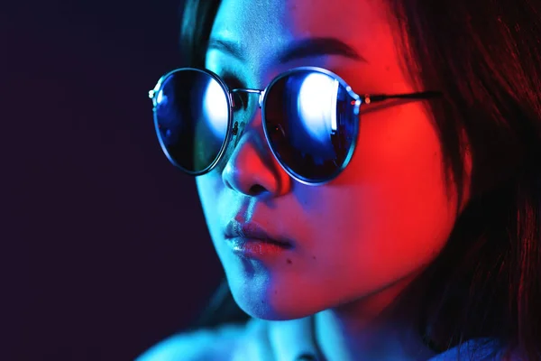 年轻的漂亮姑娘，晚上穿着霓虹灯、粉色灯和蓝色灯，看起来像亚洲人。戴眼镜的时髦少年 — 图库照片