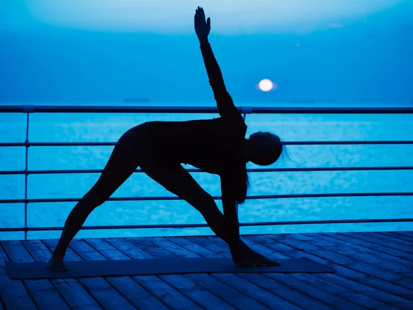 Йога під повним місяцем над нічним океаном або морським пляжем. Медитація молодих жінок під час практики . — стокове фото