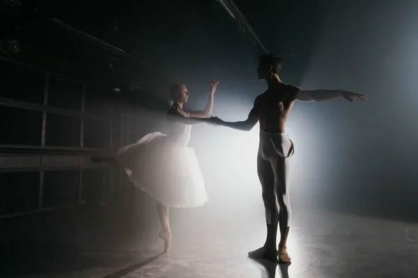 Επαγγελματικό ζευγάρι μπαλέτου που χορεύουν σε προβολείς καπνού στη μεγάλη σκηνή. Όμορφη νεαρή γυναίκα και άντρας σε φόντο προβολέων. Συναισθηματικό ντουέτο που εκτελεί χορογραφική τέχνη. — Φωτογραφία Αρχείου