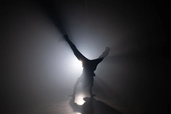 Silhouette de jeune homme breakdance, formation en studio sombre fumé. Danseuse de hip hop de rue. Entraînement en salle de gym — Photo