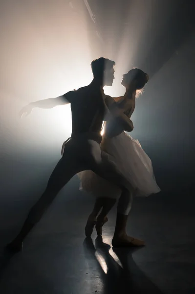 Profi balett pár táncol reflektorfényben füst a nagy színpadon. Gyönyörű fiatal nő és férfi reflektorfényben háttér. Érzelmi duett előadó koreográfia művészet. — Stock Fotó