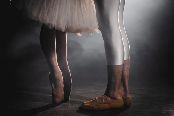 Großaufnahme eines Ballettpaares, das auf der dunklen Bühne oder im Studio Übungen macht. Frauen- und Männerfüße in Spitzenschuhen. Ballerina zeigt klassischen Ballett-Pas. Zeitlupe. Schlagschuss. — Stockfoto