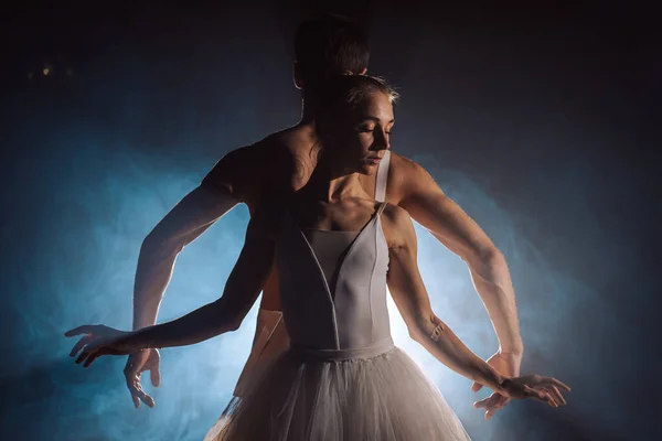 Anmutige Ballerina und ihr männlicher Partner tanzen Elemente des klassischen oder modernen Balletts im Dunkeln mit Flutlicht-Gegenlicht. Paar in Rauch auf schwarzem Hintergrund. Kunstkonzept. — Stockfoto