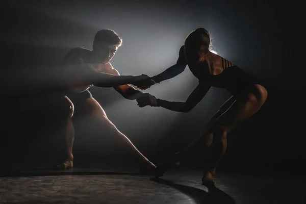 Belos acrobatas jovens ou ginastas em holofotes fundo. Casal de balé profissional dançando em holofotes fumam em grande palco. Dueto emocional realizando arte coreográfica — Fotografia de Stock