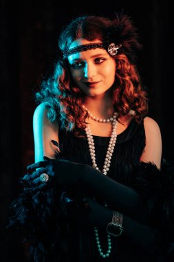 Great Gatsby dönemi tarzında giyinmiş eski moda kızıl saçlı kadının portresi. Flört ediyor ve bordo kadife arka planda poz veriyor. Vintage, flapper party, retro moda konsepti