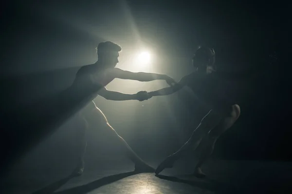 Coppia di ballerini professionisti che ballano sotto i riflettori fumano sul grande palco. Bella giovane donna e uomo su sfondo proiettori. Duetto emotivo che esegue arte coreografica . — Foto Stock