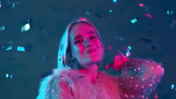Jonge hippe vrouw dansen, plezier hebben, verblijdt zich over confetti regen met neon licht in de studio. Geverfd violet haar. Concept van geluk, feest, winnen. — Stockvideo