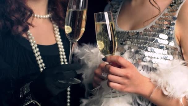 Close up glasses of champagne. Flappers women wearing in style of Roaring Gatsby twenties drinking alcohol. Vintage, retro party, fashion, girls friends concept — Stock Video