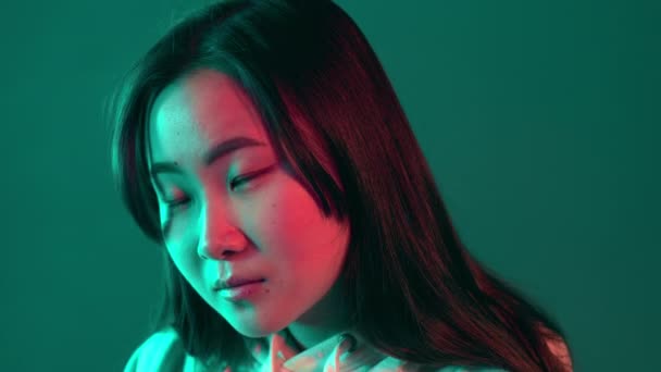 Nahaufnahme Porträt einer hübschen Koreanerin mit langer Frisur im Neonlicht. Hipster Teenager im Studio — Stockvideo