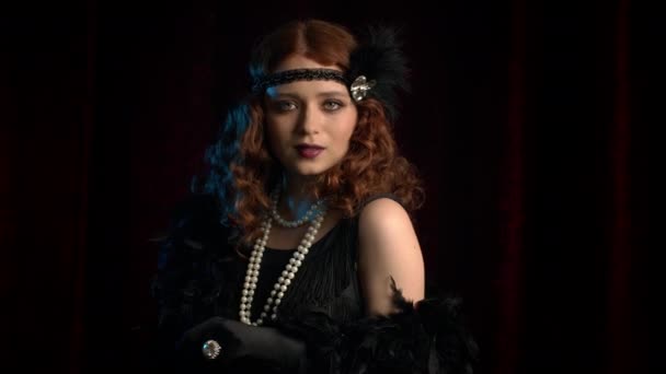 Retrato de una mujer de pelo rojo a la antigua vestida en la era de los años veinte rugiendo coqueteando y posando sobre un fondo de terciopelo borgoña. Vintage, fiesta flapper, concepto de moda retro — Vídeos de Stock