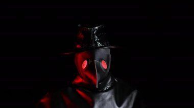 Korkmuş veba doktoru, karga benzeri maskeli, siyah arka planda izole edilmiş, karmaşa içinde ellerini sallıyor. Ürkütücü maske, cadılar bayramı, tarihi korkunç kostüm konsepti. Salgın