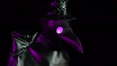 Veba doktoru kostümlü, karga gibi maskeli, siyah arka planda izole edilmiş veda jesti gösteren bir adam. Ürkütücü maske, tarihi kostüm konsepti. Salgın