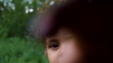 Komik çocuk kamera merceğine bakar ve sonra ilgiyle elleriyle çerçeveye tırmanmaya başlar. Tık tık, kim o? Yeşil orman geçmişi. Aile, aşk, çocuk konsepti