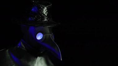 Man in plague doctor costume with crow-like mask showing middle finger - gesture of fuck. Expression negative, aggression, provocation. Creepy mask, historical costume concept. Epidemic