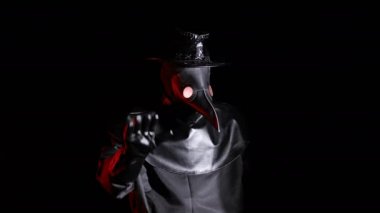 Veba doktoru kostümü giymiş, karga gibi maskeli ve el işareti olmayan bir adam. Reddetmek, reddetmek, katılmamak, siyah arka planda izole olmak. Ürkütücü maske, tarihi kostüm konsepti. Salgın