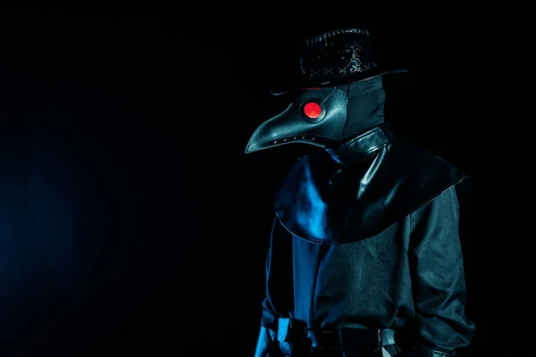 Portrait of plague doctor with crow-like mask isolated on black background. Creepy mask, halloween, historical terrible costume concept. Epidemic