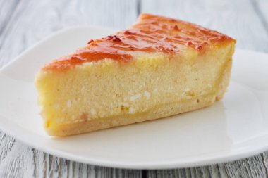 New York cheesecake ahşap arka plan üzerinde beyaz bir plaka üzerinde dilim 