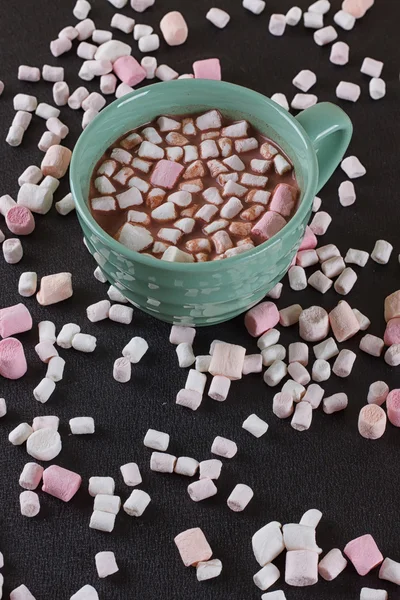 Chocolat chaud dans une tasse verte avec des guimauves éparpillées autour — Photo
