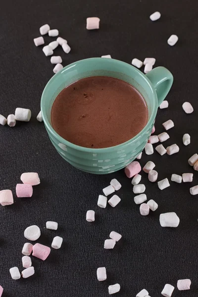 Chocolate caliente en una taza verde con malvaviscos esparcidos alrededor —  Fotos de Stock