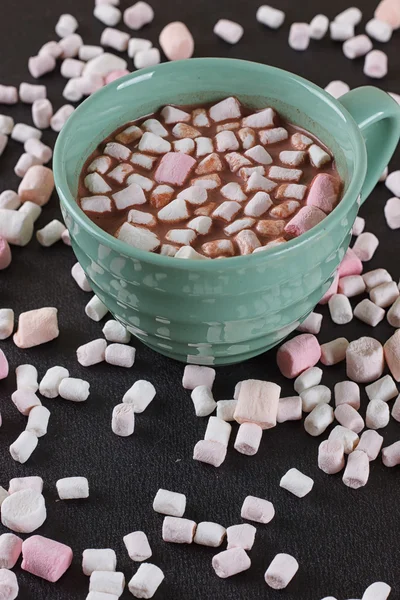 Chocolate caliente en una taza verde con malvaviscos esparcidos alrededor —  Fotos de Stock
