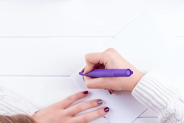 Female writing wish list in notebook near christmas gifts — Stock Photo, Image