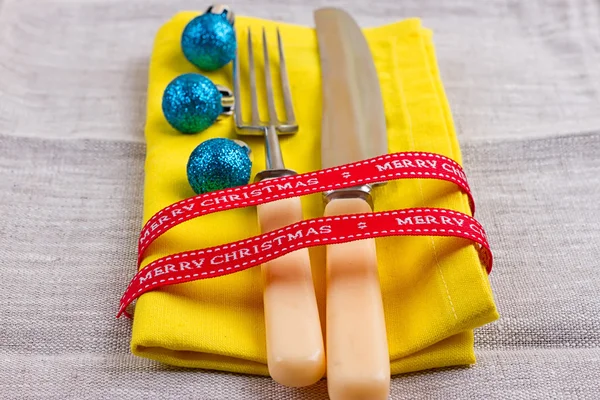 Fondo de Año Nuevo de Navidad. set tenedor, cuchillo, cuchara en servilleta amarilla con decoración Cinta de oro de vacaciones, bola azul —  Fotos de Stock
