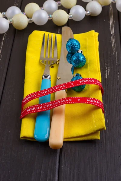 Fondo de Año Nuevo de Navidad. set tenedor, cuchillo, cuchara en servilleta amarilla con decoración Cinta de oro de vacaciones, bola azul — Foto de Stock