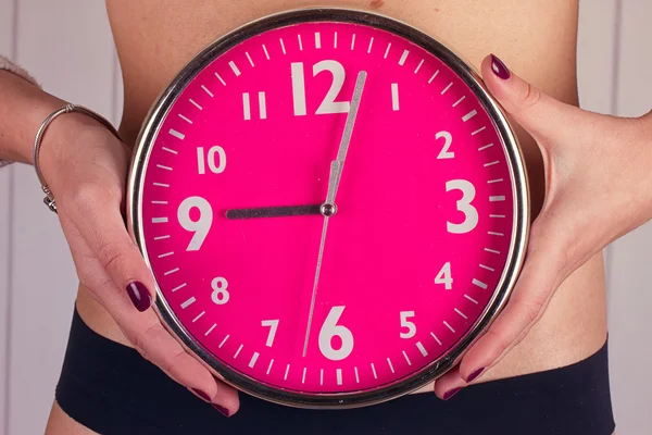 Die biologische Uhr tickt. rosa Uhr in weiblichen Händen. Straffung — Stockfoto