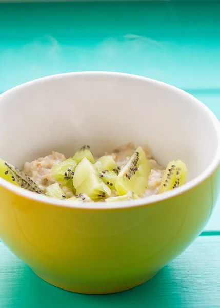 Farinha de aveia com leite e kiwi em uma tigela amarela — Fotografia de Stock