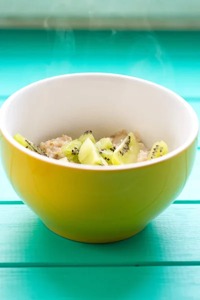 Farina d'avena con latte e kiwi in una ciotola gialla — Foto Stock