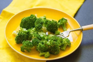 Sarı tabak içinde taze brokoli kesmek