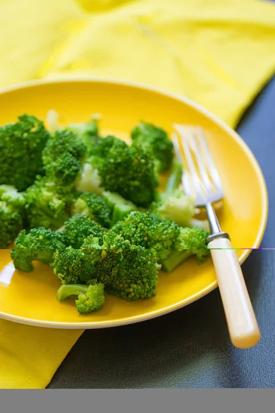Fresh broccoli cut in yellow plate — Stock Photo, Image