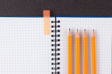 Açık not defteri ve siyah arka plan üzerinde renkli kalemler