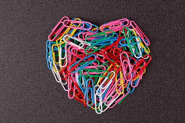 Різноманітні кольорові скріпки паперу розташовані у формі серця — стокове фото