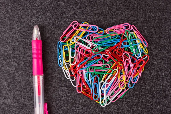 Різноманітні кольорові скріпки паперу розташовані у формі серця — стокове фото