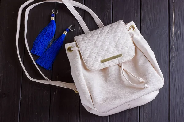 Pequeña mochila de mujer de cuero blanco y pendientes azules de hilo — Foto de Stock