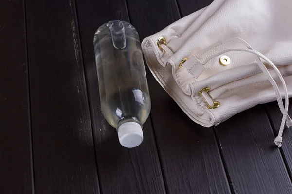 Белый кожаный рюкзак и бутылка воды — стоковое фото