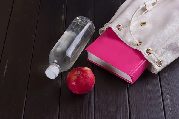 Mochila de cuero blanco, libro rosa, botella de agua — Foto de Stock