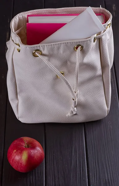 Белый кожаный рюкзак, яблоко, тюбик сливок — стоковое фото