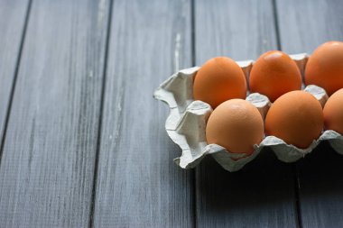 Siyah ahşap zemin üzerine karton yumurta kutusu