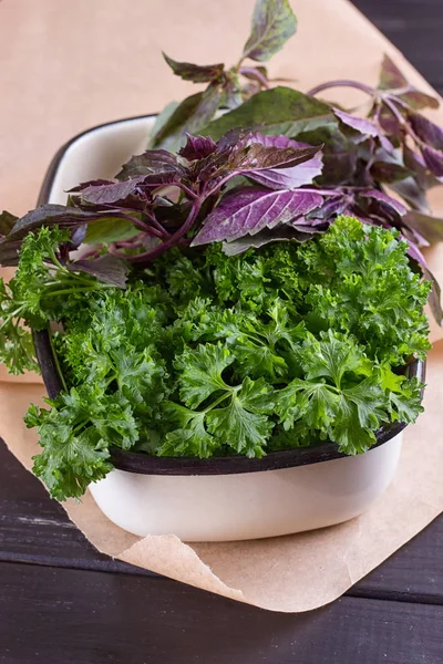 A bunch of fresh parsley in a ceramic tray on a black background. — Stock Photo, Image