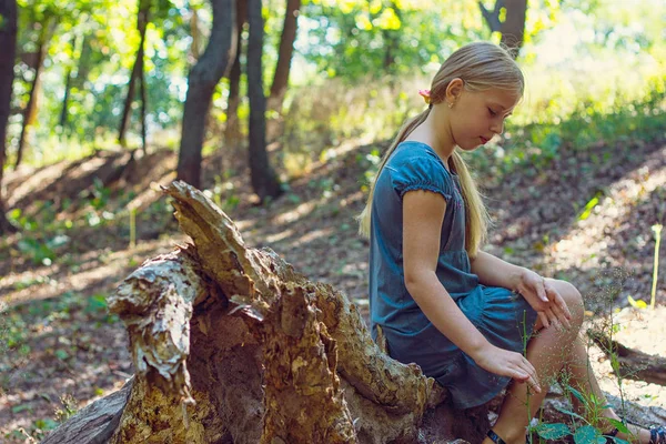 Dziewczyna siedzi na pniu drzewa — Zdjęcie stockowe