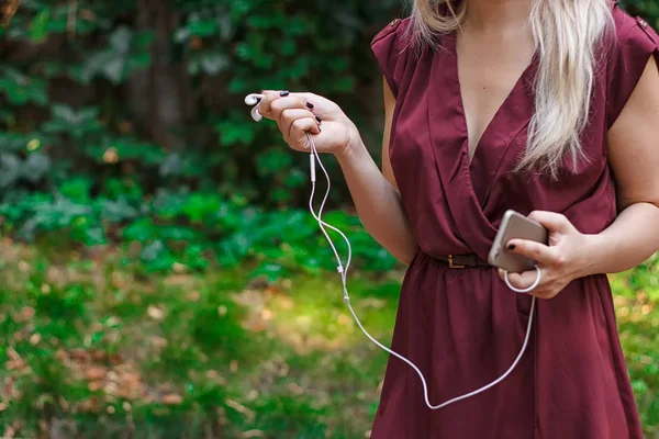 Auriculares desde un teléfono móvil en manos femeninas — Foto de Stock