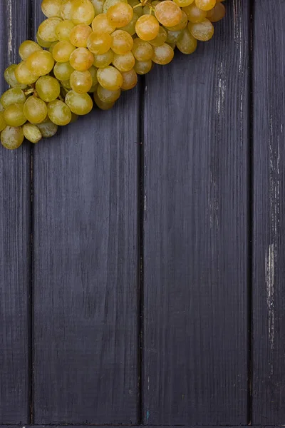 Cacho de uvas brancas em um fundo de madeira preta — Fotografia de Stock