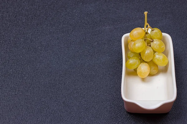 Uvas brancas em uma tigela em um fundo preto — Fotografia de Stock