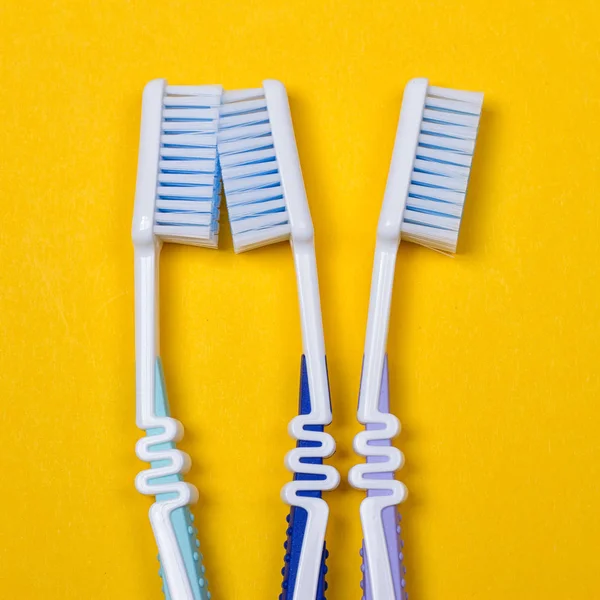 Three Toothbrushes on yellow background — Stock Photo, Image