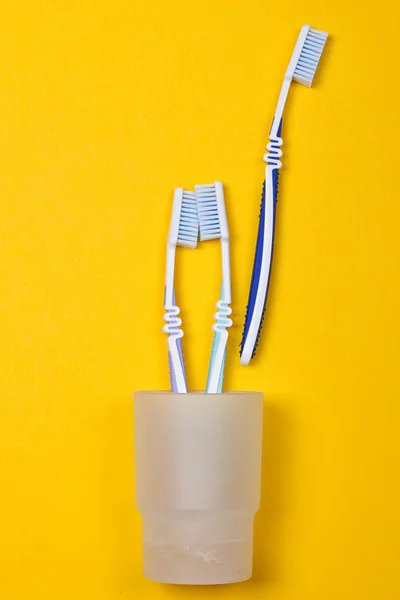 Three toothbrushes in a glass — Stock Photo, Image