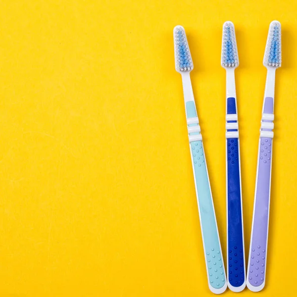 Three Toothbrushes on yellow background — Stock Photo, Image