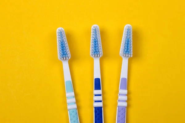 Three Toothbrushes on yellow background — Stock Photo, Image